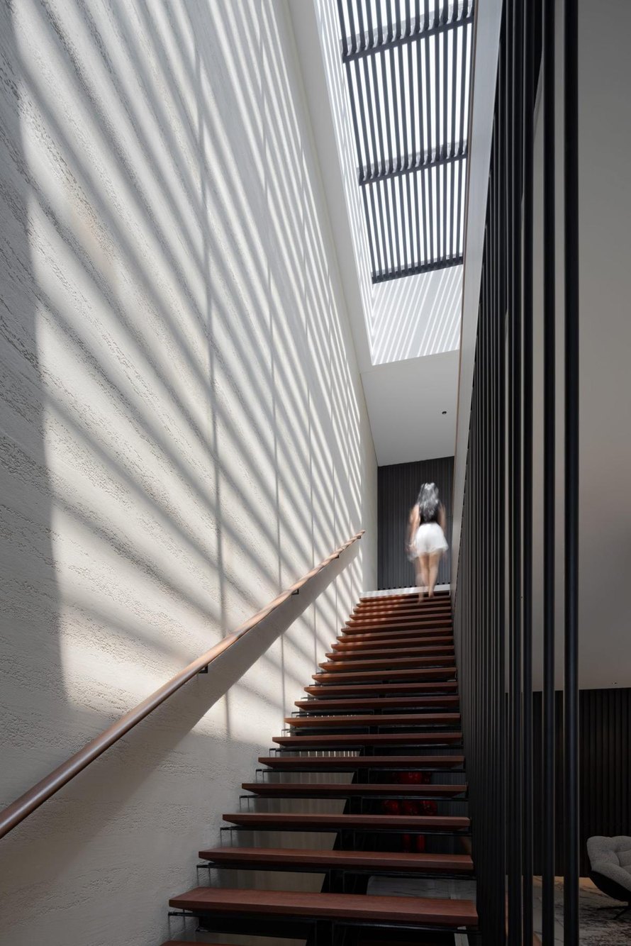 Tangga kayu AD House di bawah skylight dengan dinding bersirip