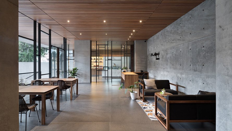 Ruang bersama Nagomi Suites dengan beton ekspos dan plafon kayu